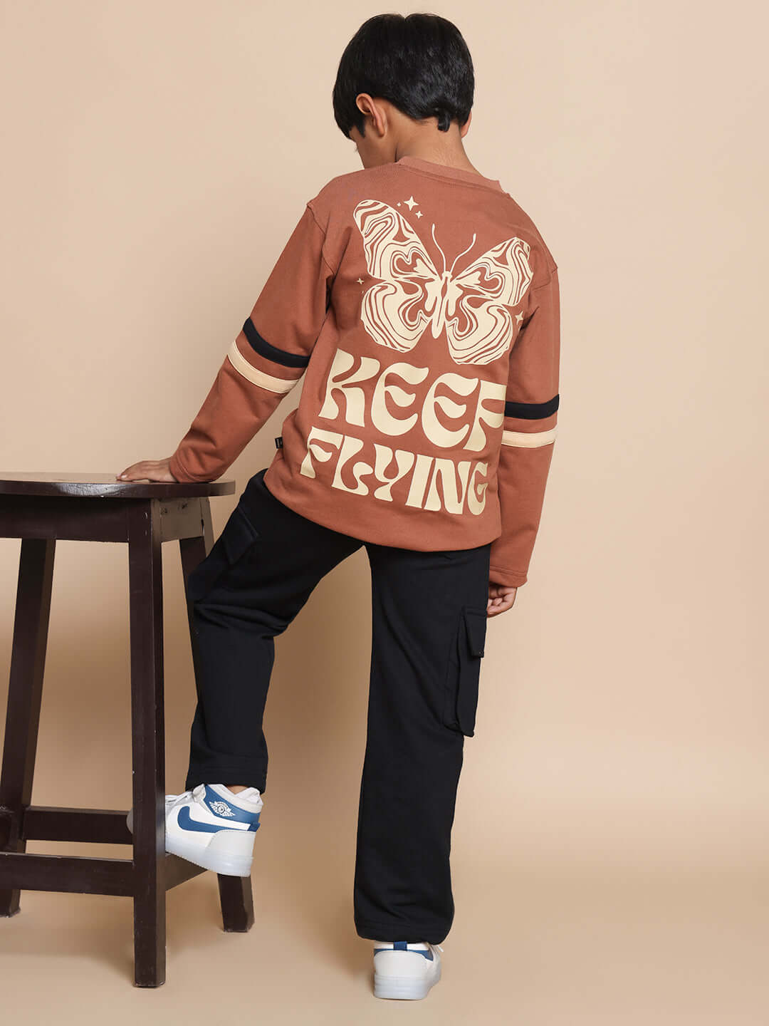Boy wearing KEEP FLYING brown-black co-ord outfit, featuring a butterfly design on the top. Casual and trendy kids fashion. Made-to-order.