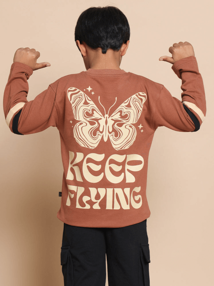 Brown oversized sweatshirt with 'Keep Flying' text and butterfly design on the back, modeled by a child, available for boys and girls.