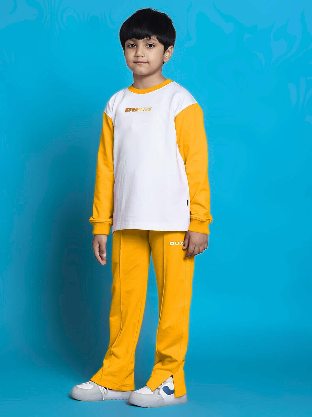 Child wearing a white and yellow KEVIN co-ord set for boys and girls, featuring relaxed fit joggers and a long-sleeve top.