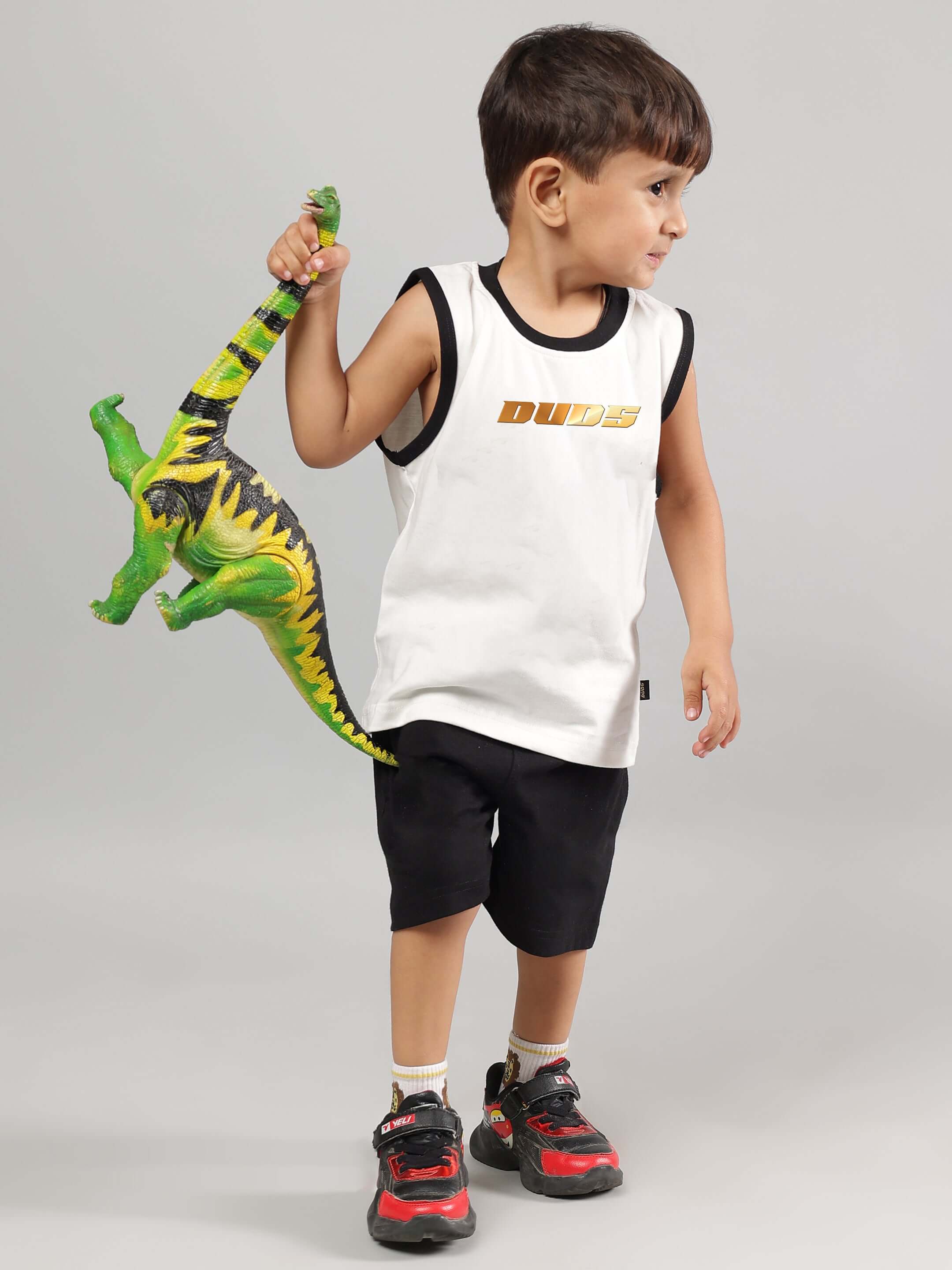 Young child in DUDS off-white and black summer co-ord set holding a toy dinosaur.