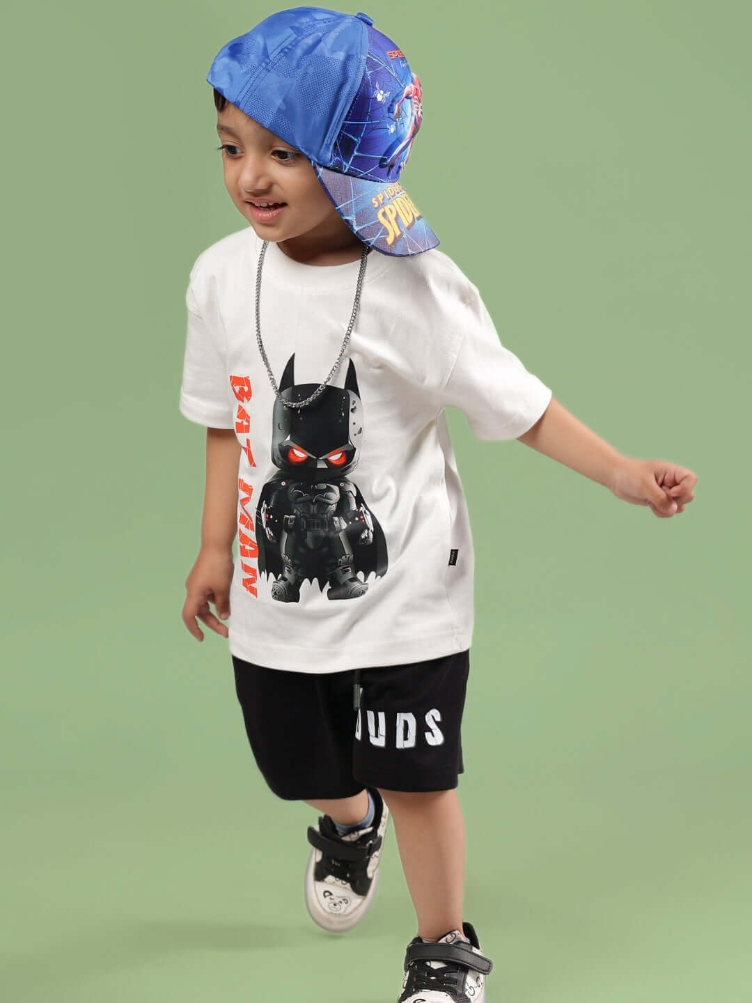 Child wearing Batman-themed t-shirt and shorts, running and smiling.