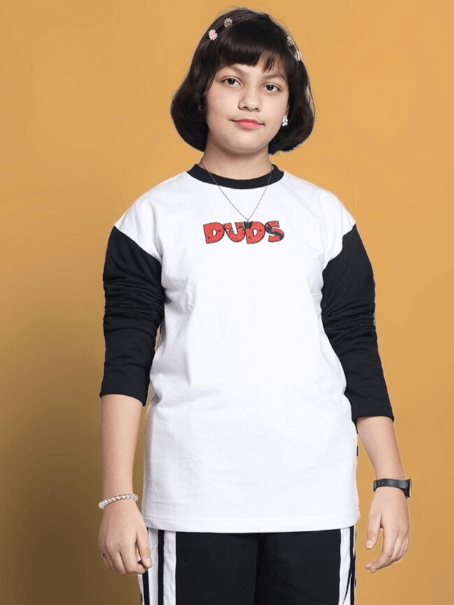 Child wearing BITSY oversized white sweatshirt by DUDS, featuring black sleeves and red logo on front, standing against a yellow background.