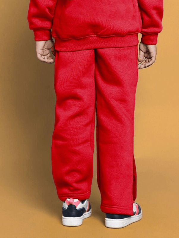 Child wearing red Born to Shine jogger set, showcasing comfortable, stylish pants and sneakers against a warm background.