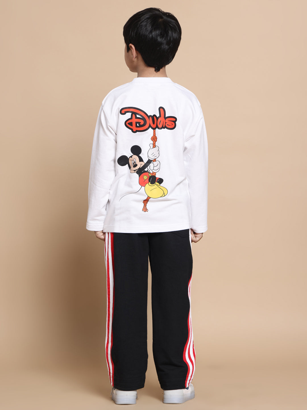Back view of a child wearing a white shirt with a cartoon graphic, paired with black pants.