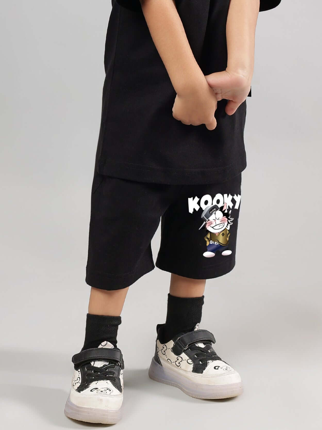 Child wearing Kooky black shorts for boys and girls with cartoon design, custom sizing available, made by DUDS Tailors.