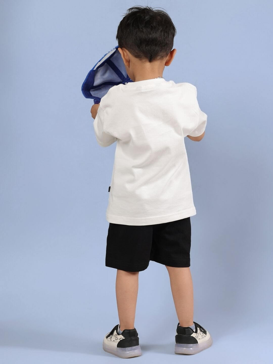 Child wearing Kung Fu Panda co-ord set with off-white T-shirt and black shorts, standing on blue background.