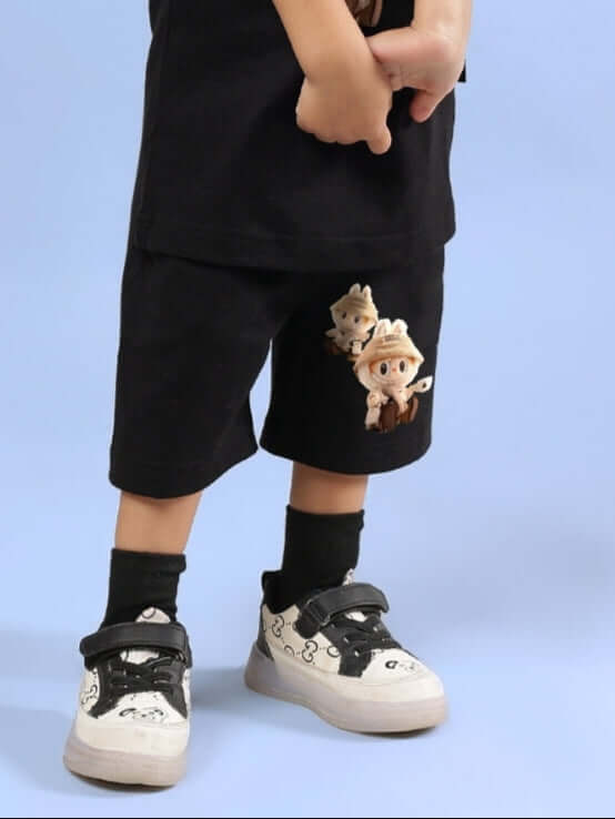 Child wearing Labubu Gang black shorts, featuring cartoon characters, paired with white sneakers and black socks on a light blue background.