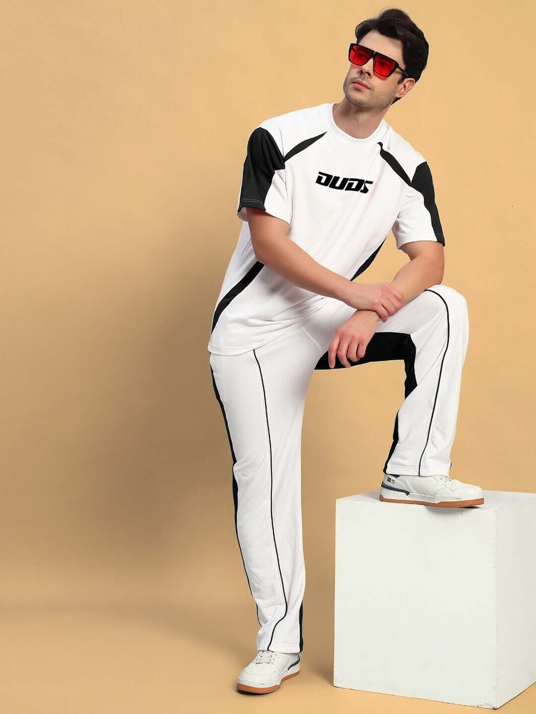 Model wearing LAGOON RELAXED FIT JOGGERS WHITE BLACK by DUDS, showcasing relaxed style on beige background.