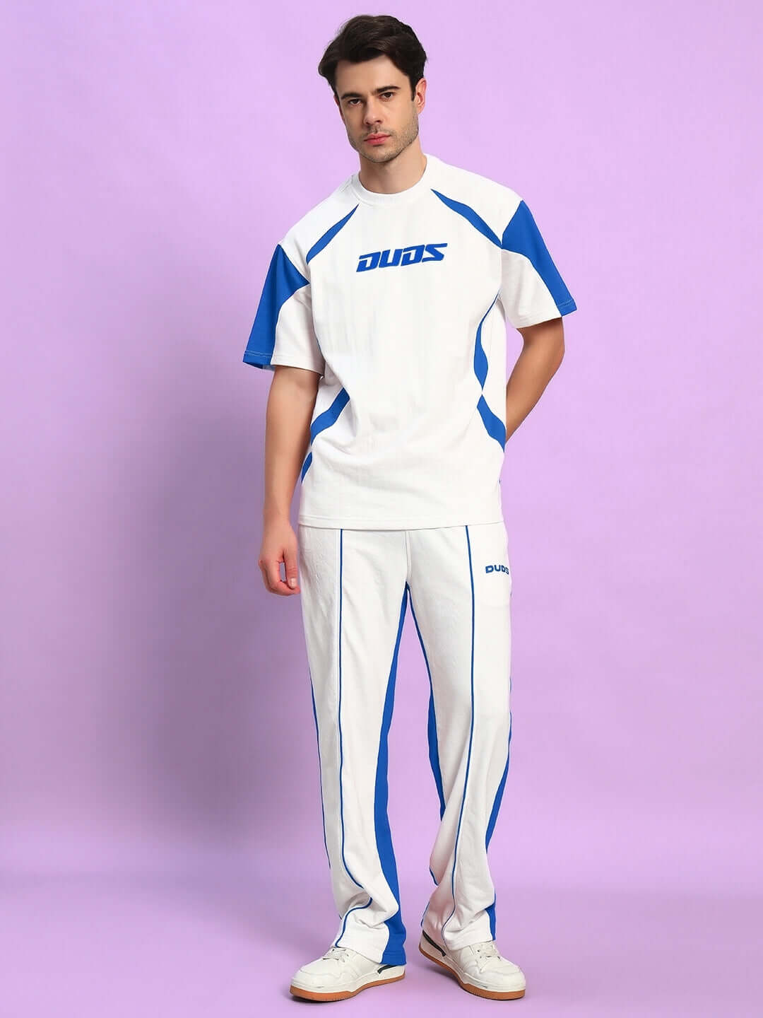 Alt Tag: Model wearing LAGOON RELAXED FIT JOGGERS WHITE BLUE with matching blue accents on a purple background.