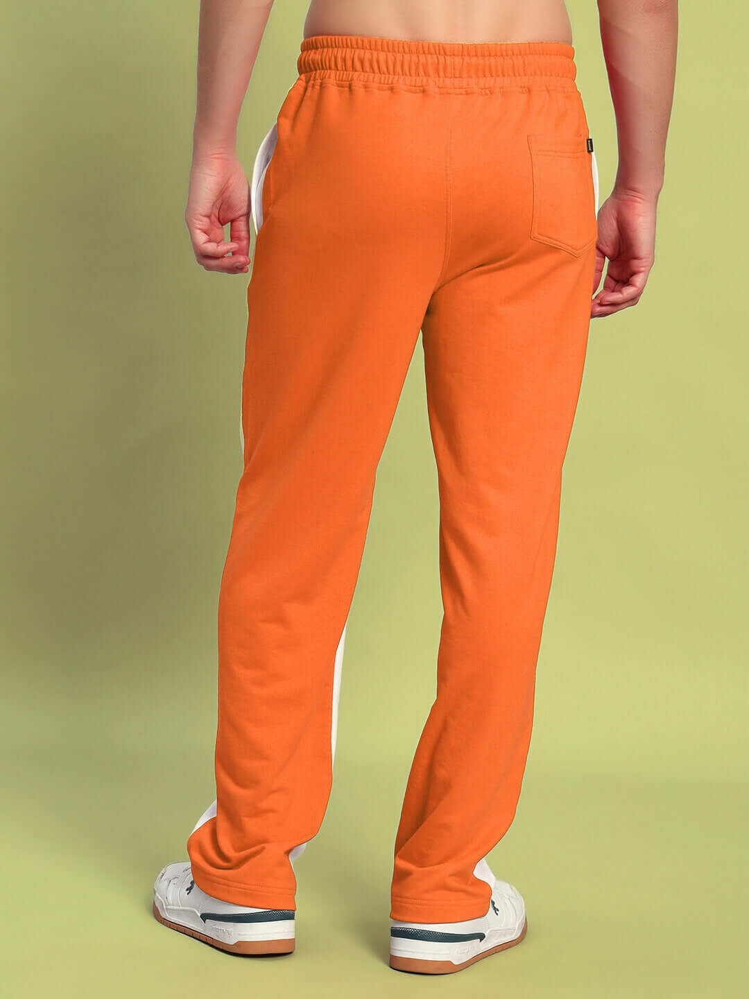 Model wearing orange and white Lagoon relaxed fit joggers, showcasing back view with elastic waistband and rear pocket detail.