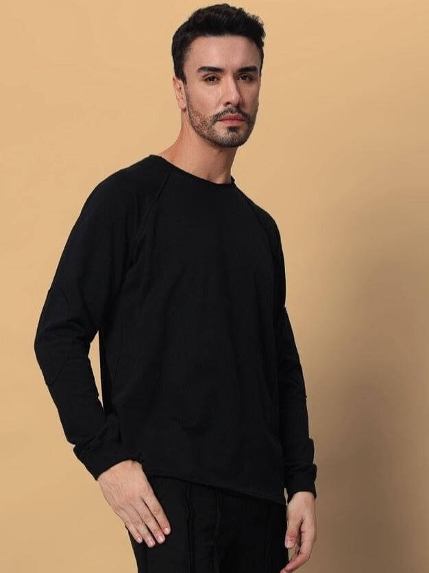 Man wearing a black oversized sweatshirt made from premium cotton fabric, emphasizing comfort and style.
