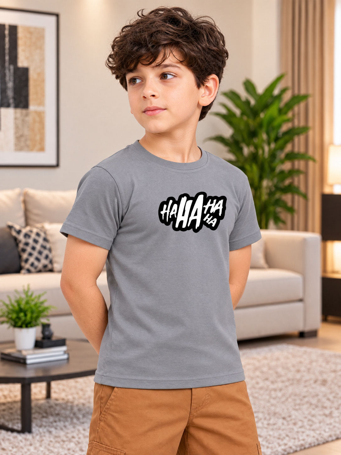 LAUGH GRAPHIC T-SHIRT FOR BOYS GIRLS GREY worn by a boy with HAHAHA print in a cozy living room setting