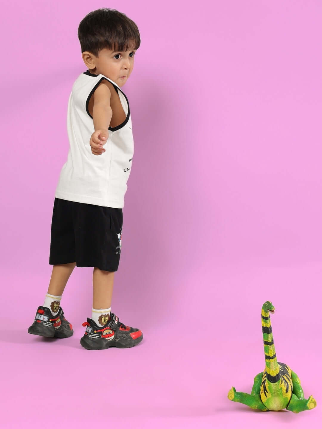 Child wearing LAZIO CO-ORD FOR BOYS & GIRLS OFF WHITE-BLACK with toy dinosaur on pink background