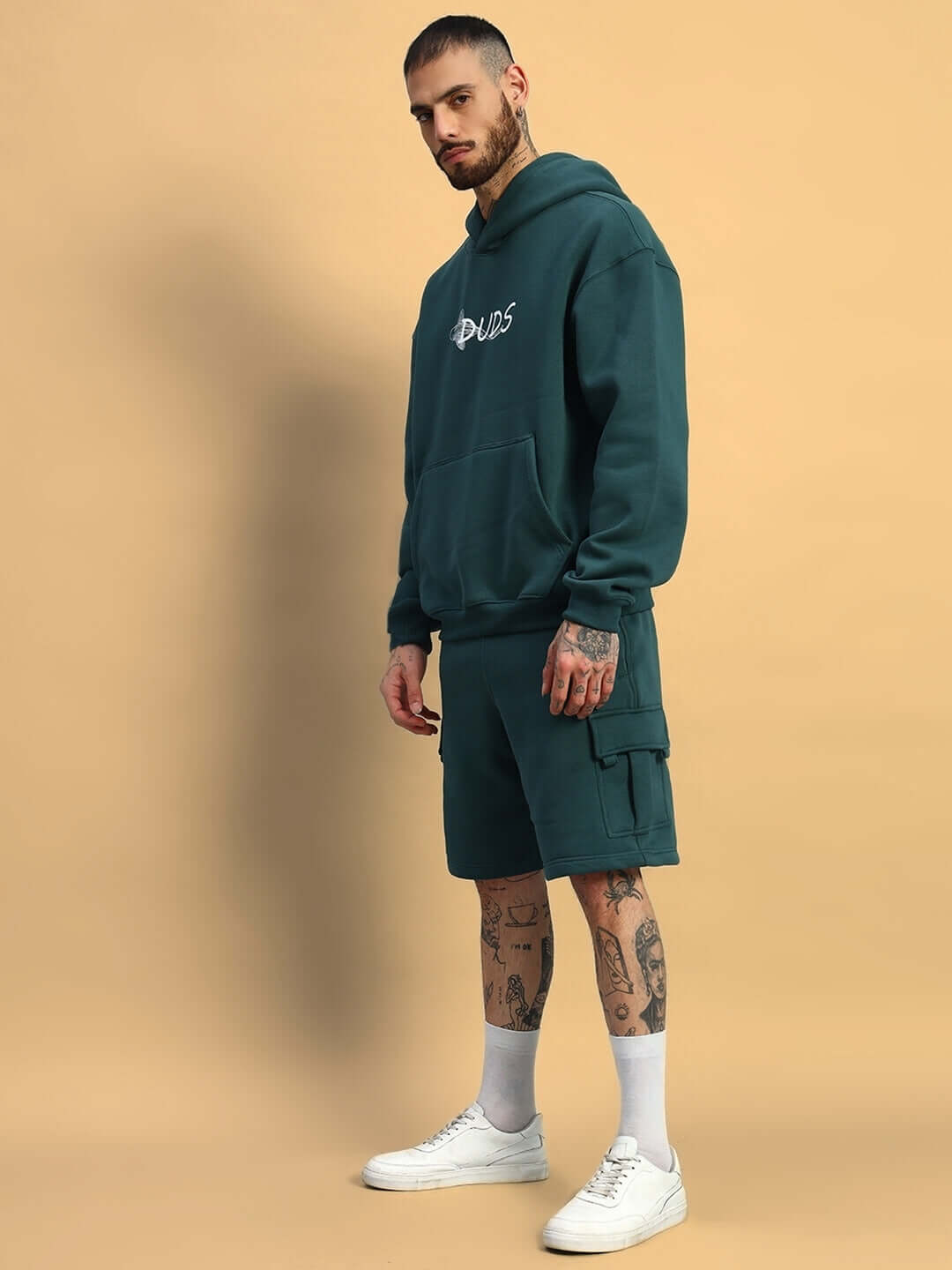 Man wearing LEOPARD SHARK FLEECE CO-ORD TEAL GREEN, showcasing trendy streetwear in a stylish teal outfit with a hoodie and shorts.