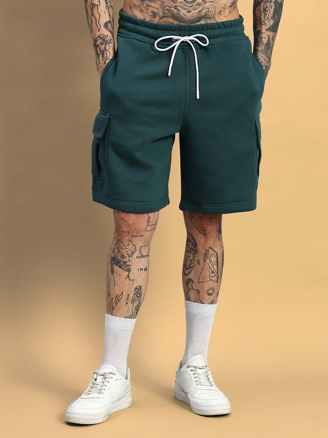 Man wearing LEOPARD SHARK FLEECE CO-ORD TEAL GREEN shorts with white sneakers, showcasing contemporary streetwear style.