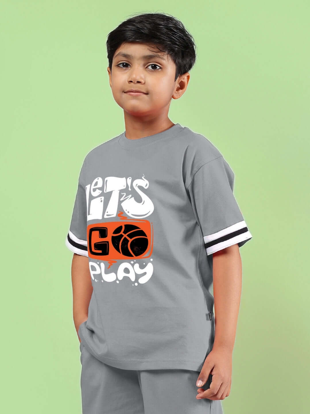 Child wearing LETS GO PLAY PRINTED T-SHIRT FOR BOYS & GIRLS GREY on green background