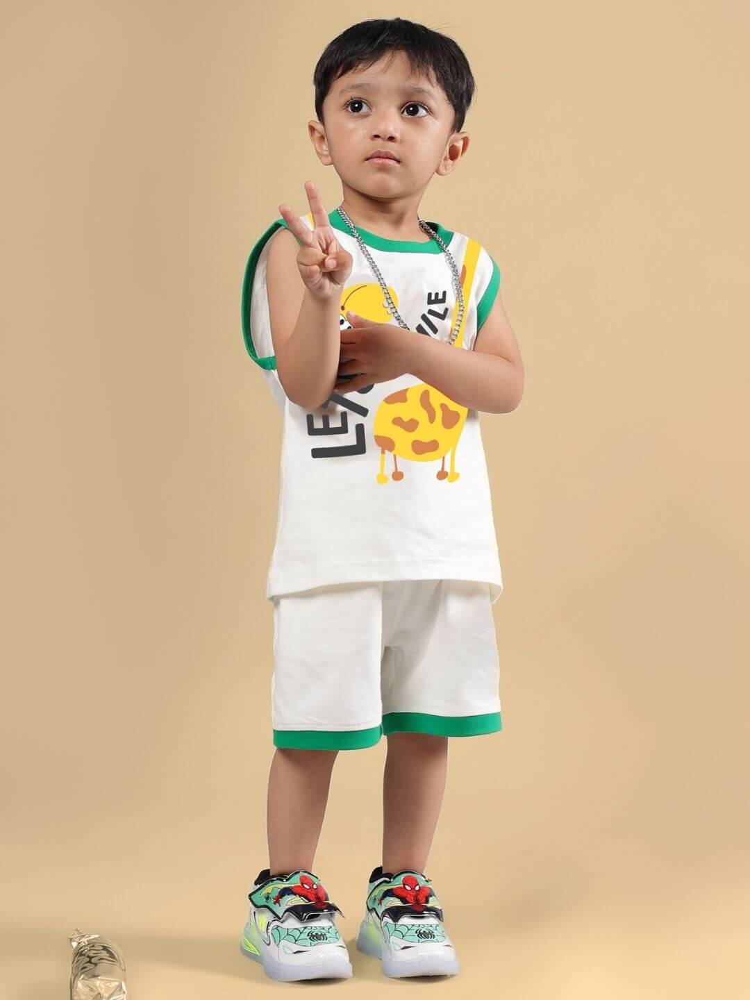 Child wearing Let's Smile Co-Ord set in off white with graphic print and green trim, posing against beige background.