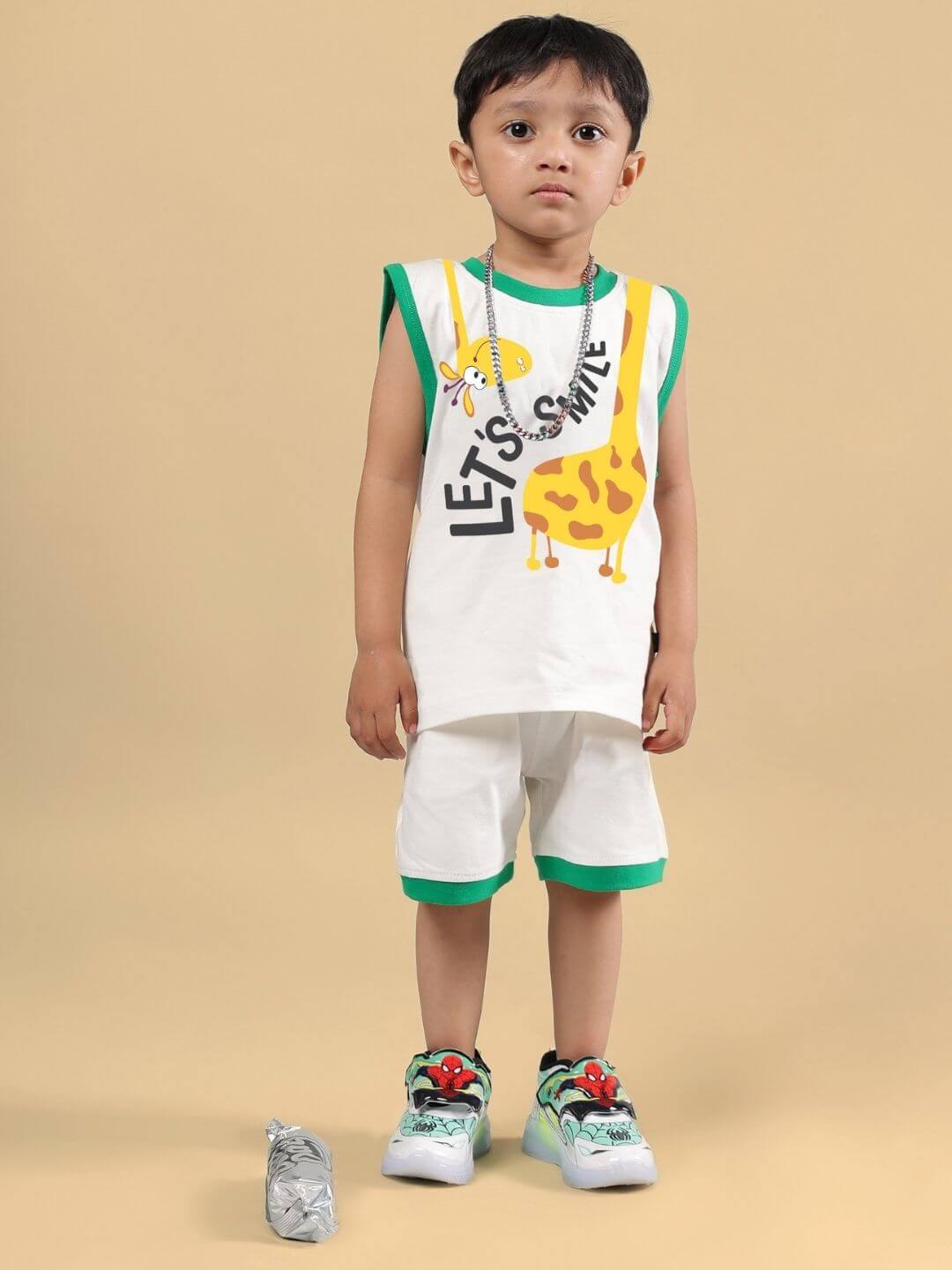 Child wearing Let's Smile Co-Ord in off white with giraffe print, matching shorts, green trim, and colorful sneakers.