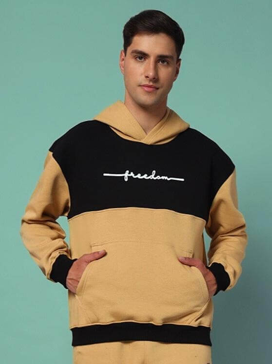 Model wearing LIBERTY FLEECE COLORBLOCK HOODIE BEIGE BLACK, showcasing trendy streetwear with bold beige and black colorblocking style.