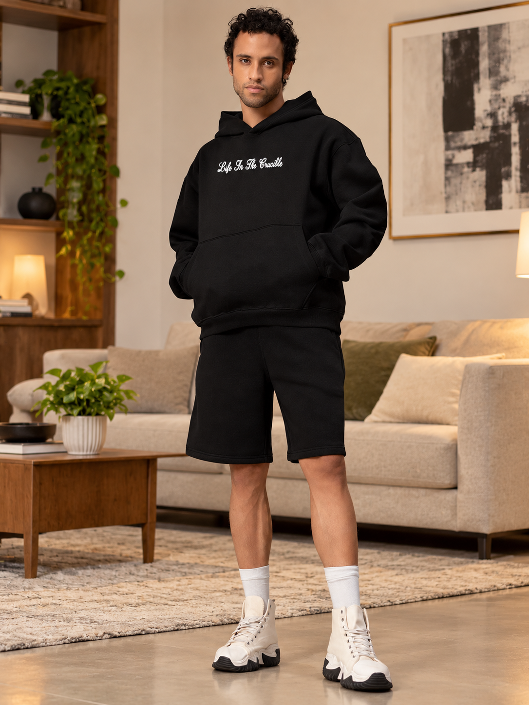 Man wearing LIFE IN THE CRUCIBLE PRINTED FLEECE CO-ORD BLACK hoodie and shorts set in stylish living room
