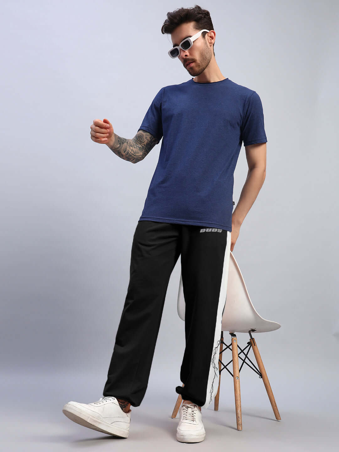 Model wearing LIGHTNING BOLT RELAXED FIT JOGGERS BLACK-WHITE with blue t-shirt and sneakers, showcasing streetwear style.