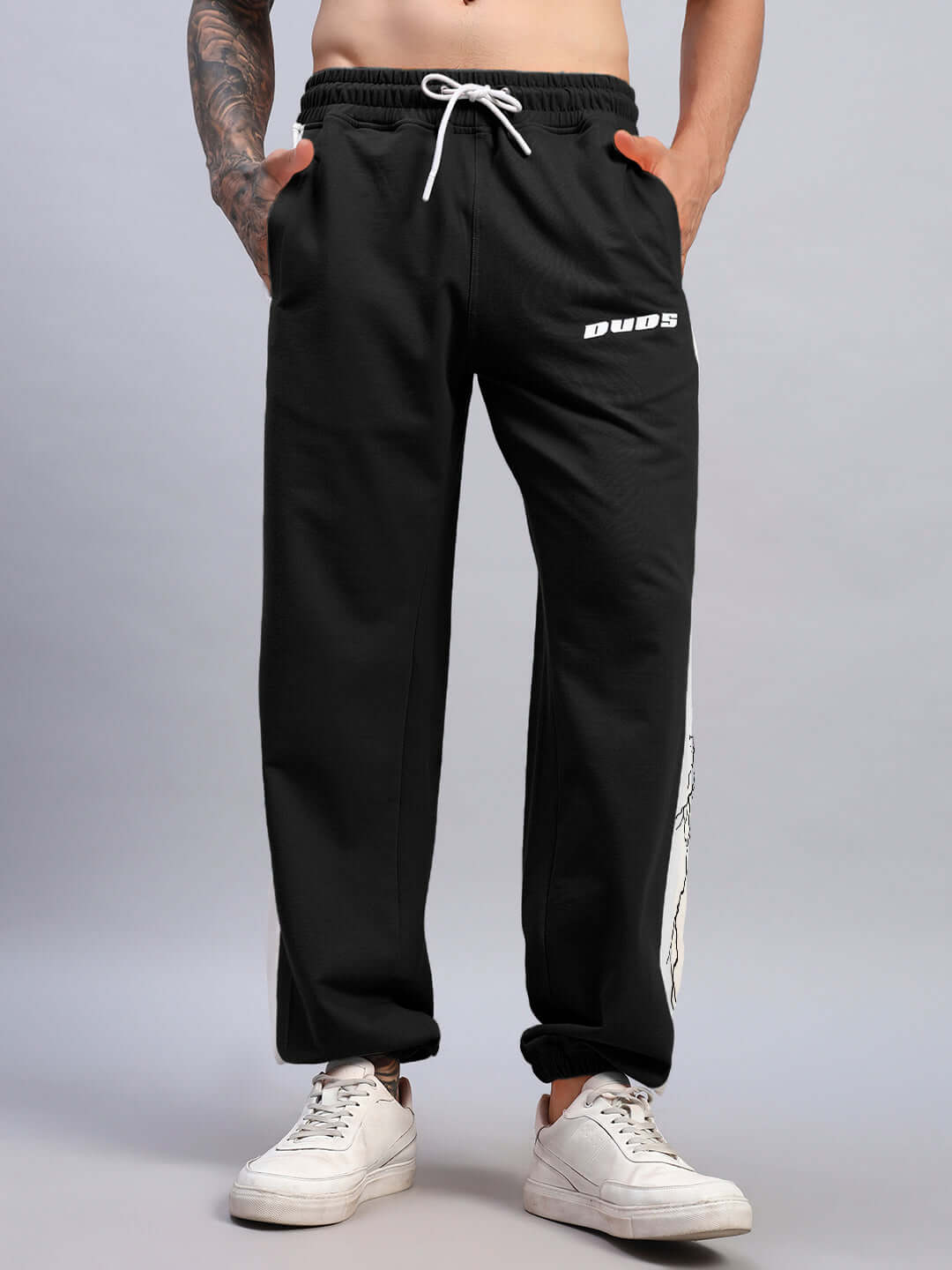 Man wearing LIGHTNING BOLT RELAXED FIT JOGGERS BLACK-WHITE showing off casual streetwear style with white sneakers.