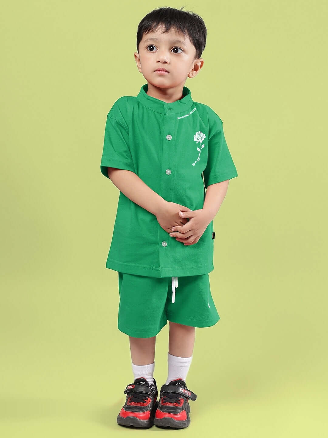 Child wearing LIMBO CO-ORD FOR BOYS & GIRLS GREEN, featuring a relaxed-fit green shirt and shorts on a vibrant background.