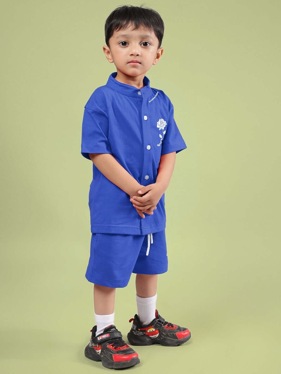 Child wearing LIMBO CO-ORD FOR BOYS & GIRLS BLUE, a stylish blue shirt and shorts set, standing against a green background.