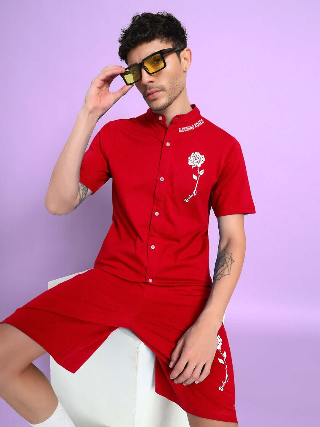 Man wearing red LIMBO CO-ORD set with short-sleeve shirt, matching shorts, and sunglasses against a purple background.