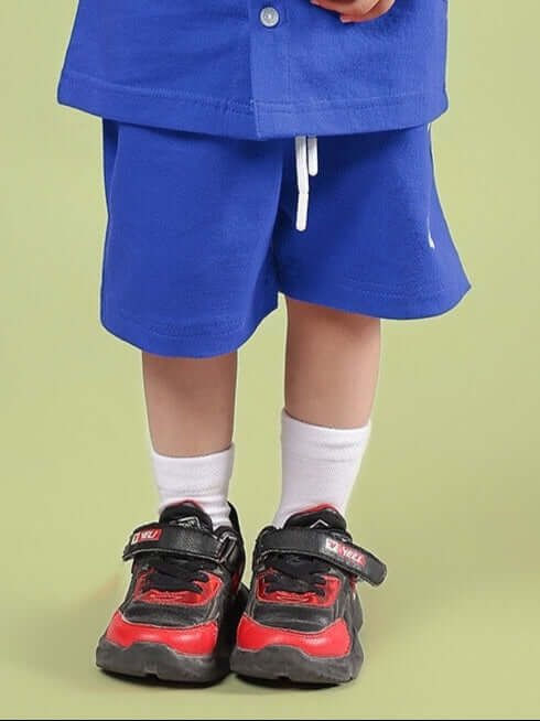 Child wearing LIMBO SHORTS FOR BOYS & GIRLS BLUE and red sneakers, perfect for active play and comfort.