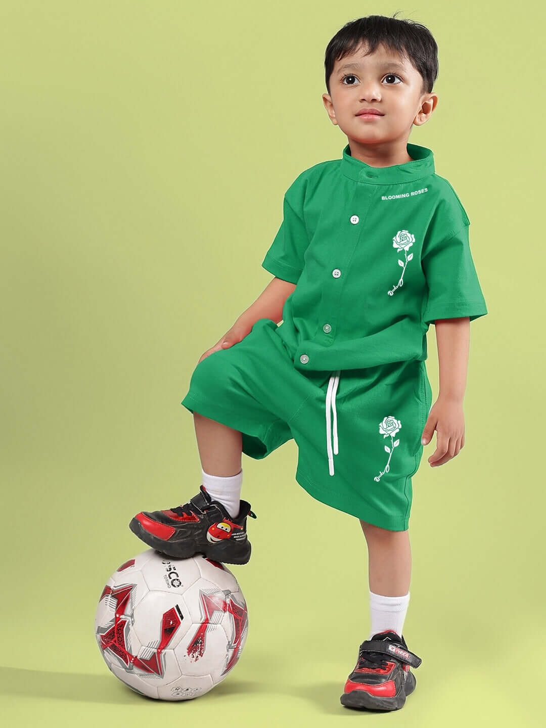 Child wearing LIMBO SHORTS FOR BOYS & GIRLS GREEN, standing with a soccer ball, showcasing comfortable and stylish cotton-blend outfit.