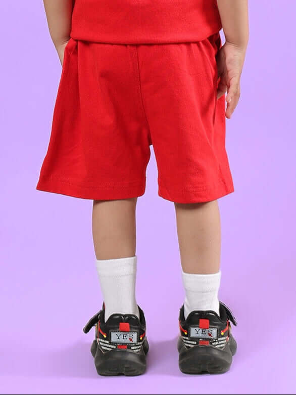 Child wearing LIMBO SHORTS FOR BOYS & GIRLS RED, made to order with customization options, shown from the back on a purple background.