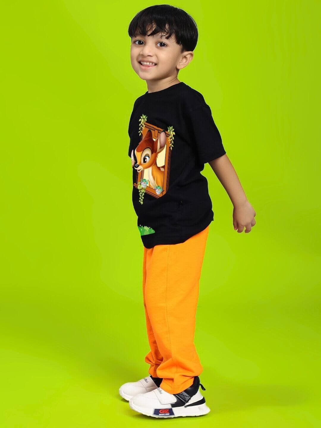 Child wearing LIMITED EDITION JOGGER FOR BOYS AND GIRLS ORANGE with black shirt on green background, showcasing vibrant and playful fashion.