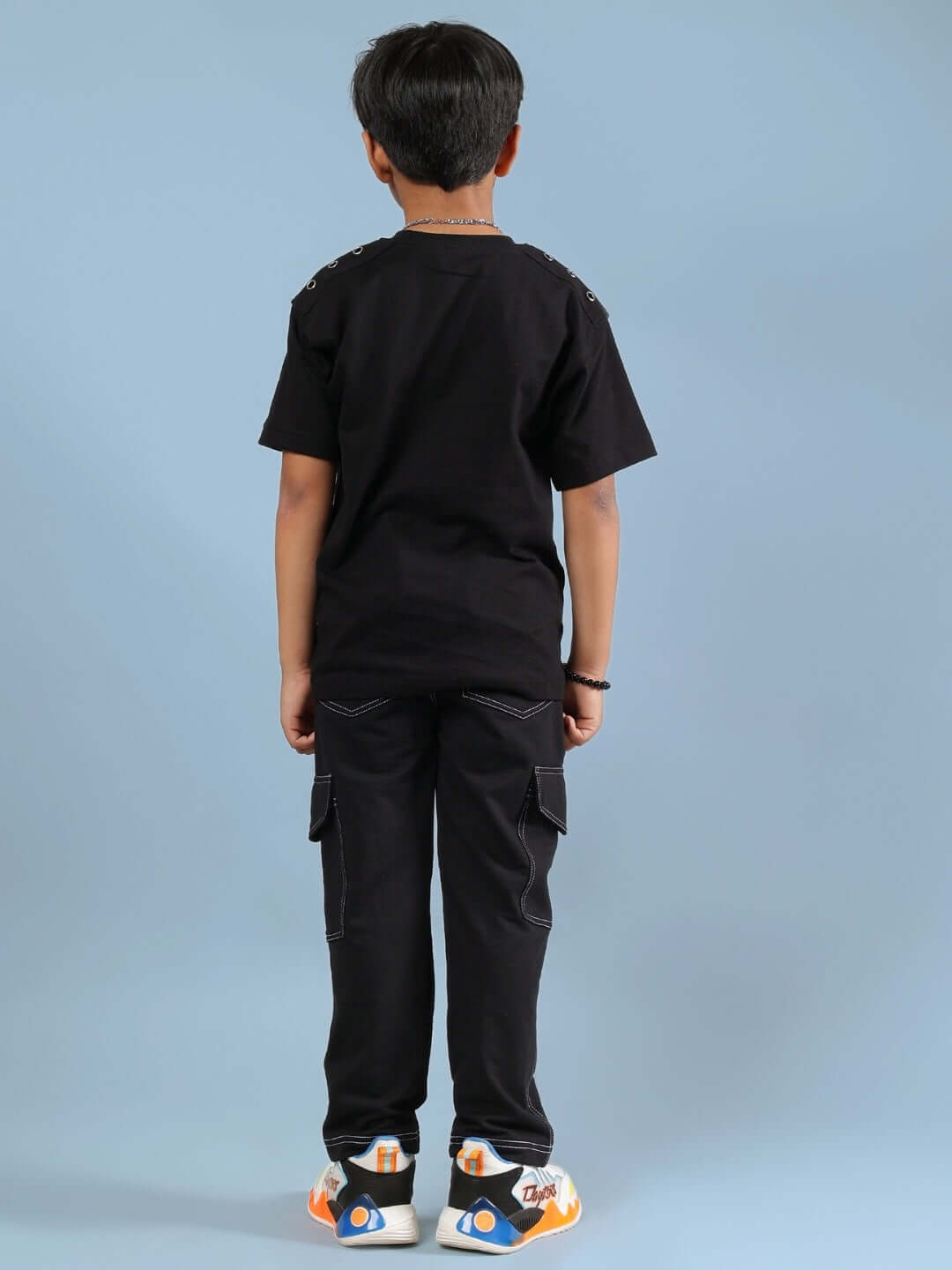 Boy wearing LIMITLESS CO-ORD FOR BOYS GIRLS BLACK outfit, standing with back facing camera, on a light blue background.