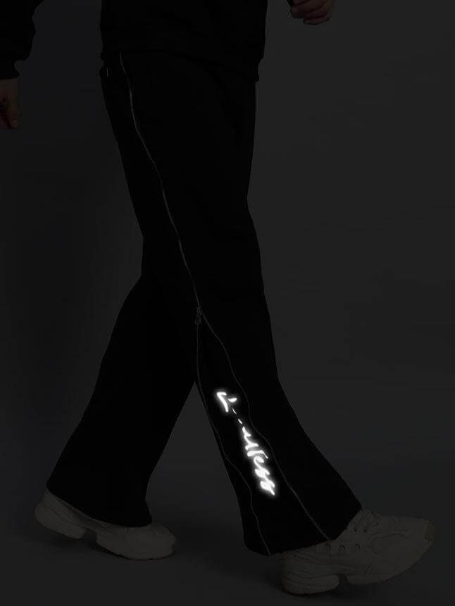 Person wearing LIMITLESS FLEECE REFLECTOR JOGGER BLACK with reflective detailing, showcasing streetwear style.