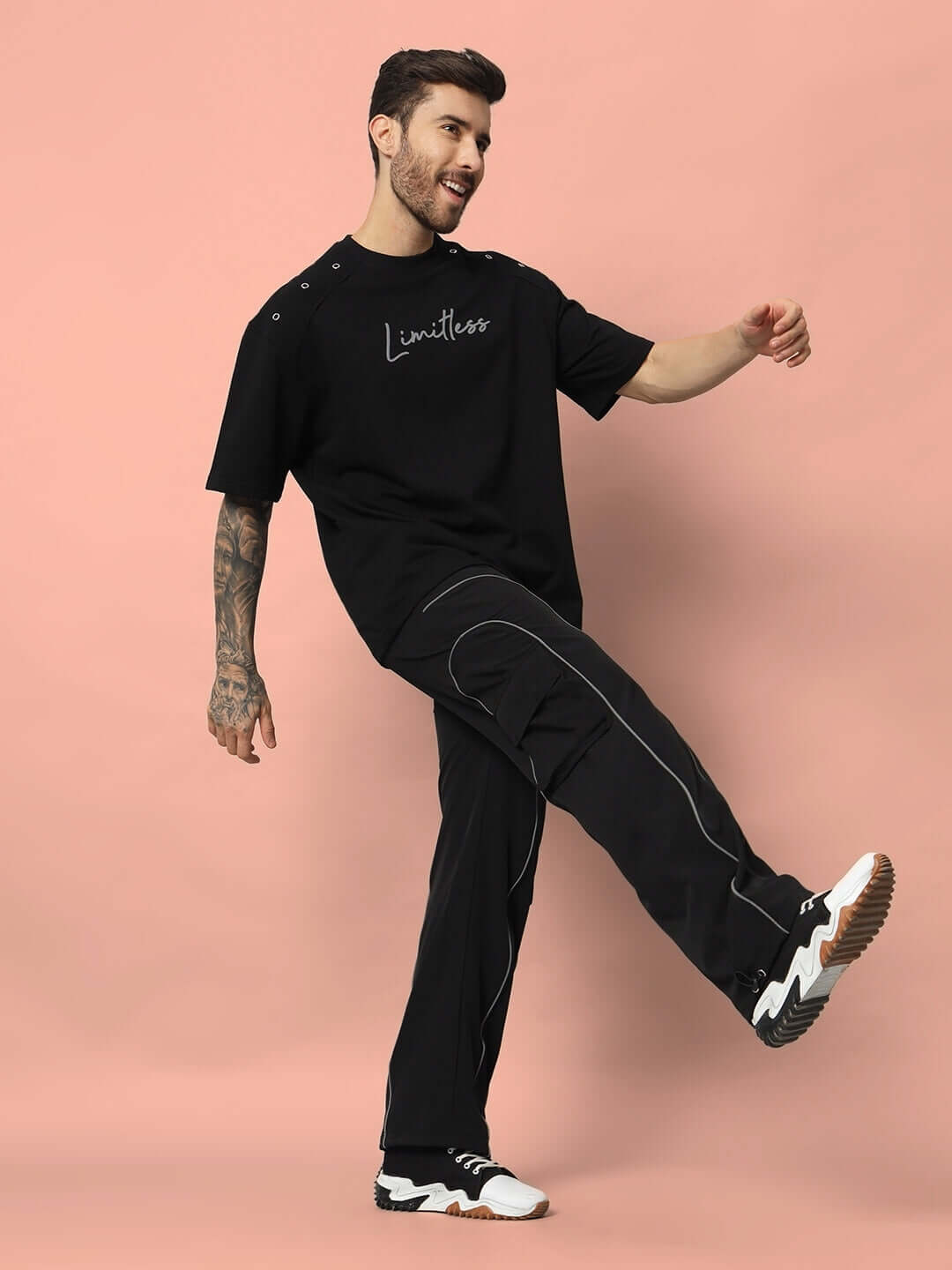 Man wearing Limitless Reflector over-sized black t-shirt made from premium cotton fabric, designed for comfort and style, against a peach background.