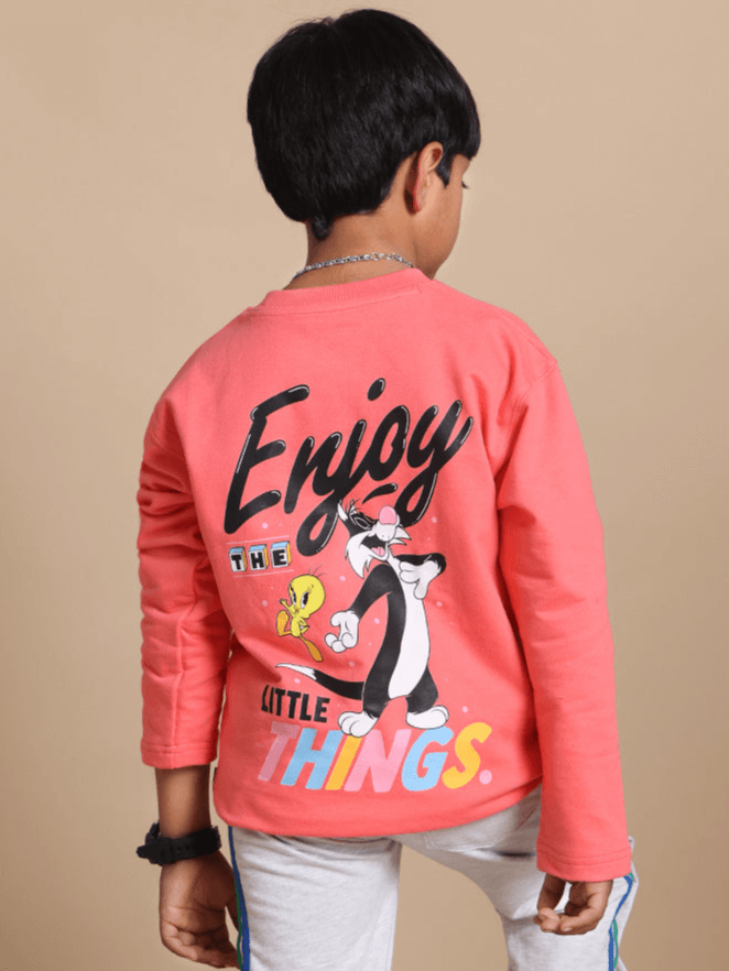 Child wearing a peach oversized sweatshirt with cartoon design, showcasing the "Enjoy the Little Things" slogan, ideal for boys and girls.