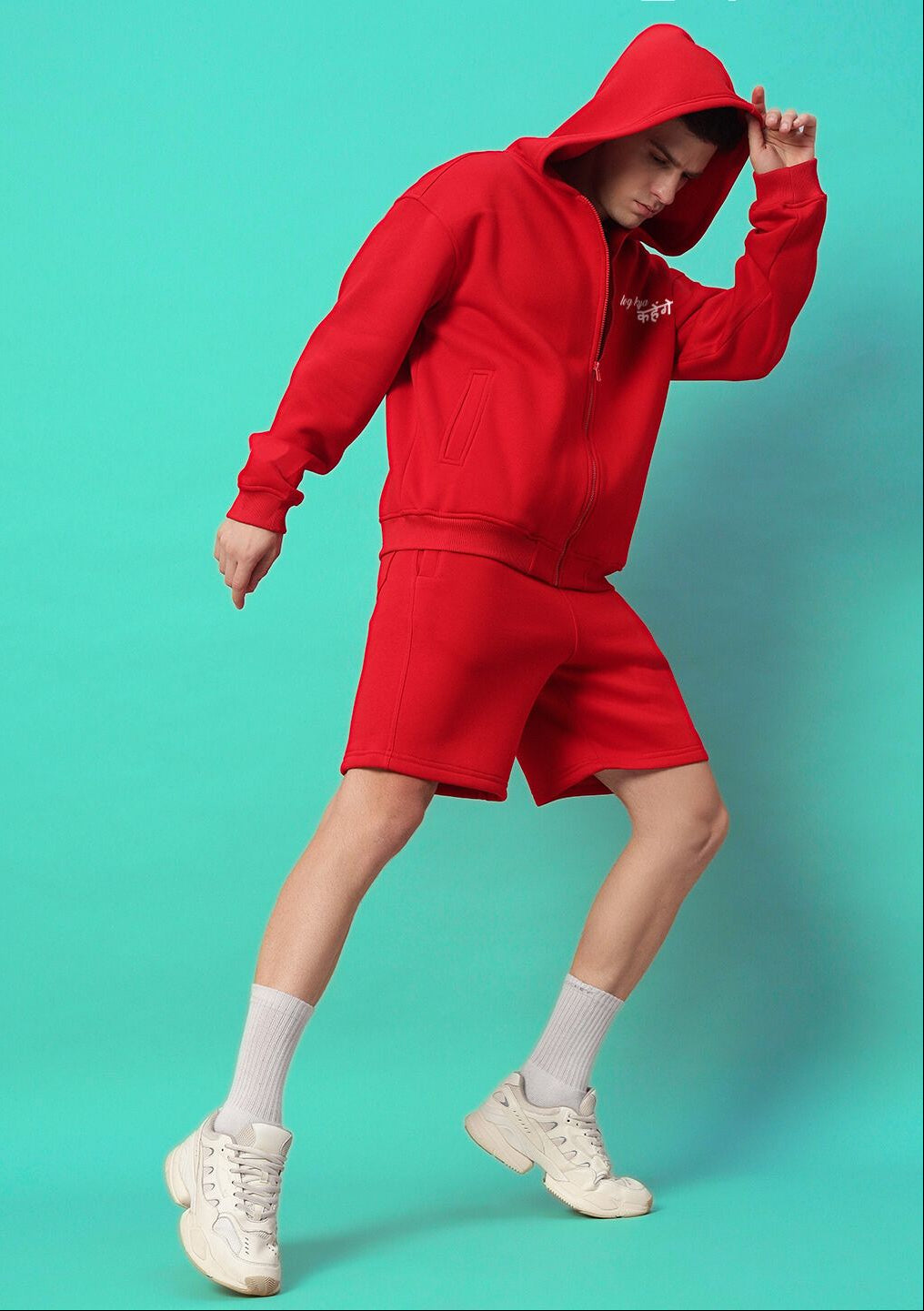 Person wearing A LOOK ATTITUDE FLEECE HOODIE RED with matching shorts against a turquoise background.