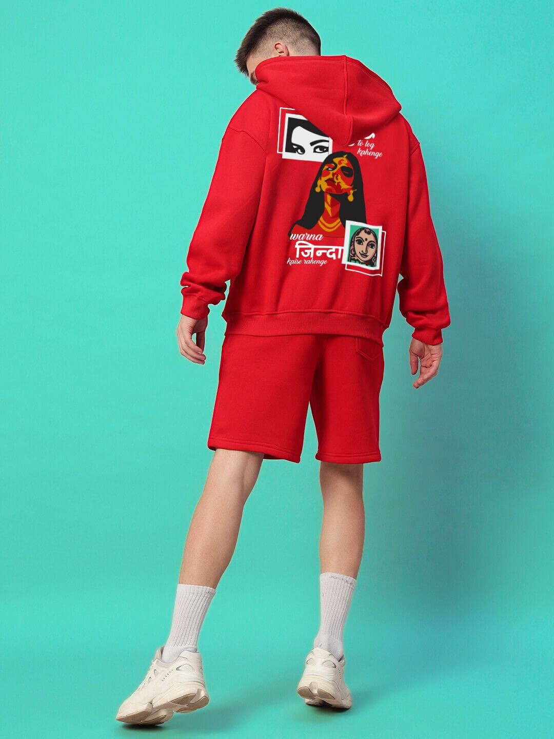 Person wearing A LOOK ATTITUDE FLEECE CO-ORD RED outfit with graphic hoodie and shorts, standing against turquoise background.