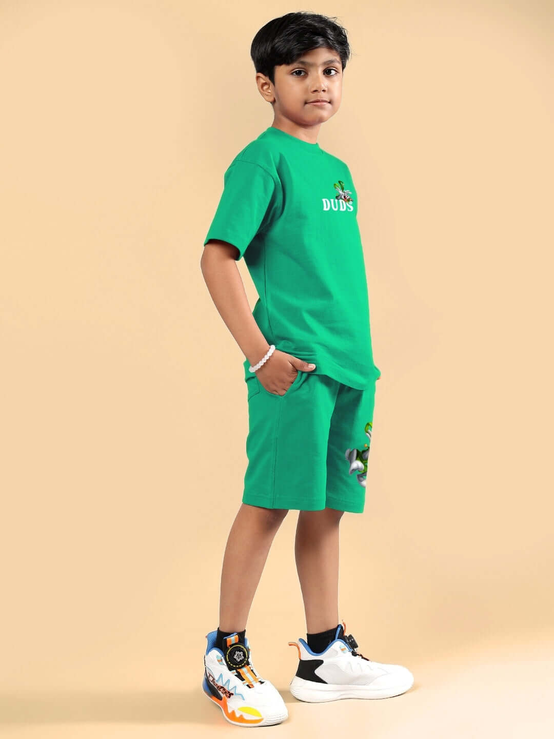 LOONEY TUNES PRINTED CO-ORD FOR BOYS & GIRLS GREEN worn by a child standing in a green outfit with sneakers, made to order by skilled tailors.