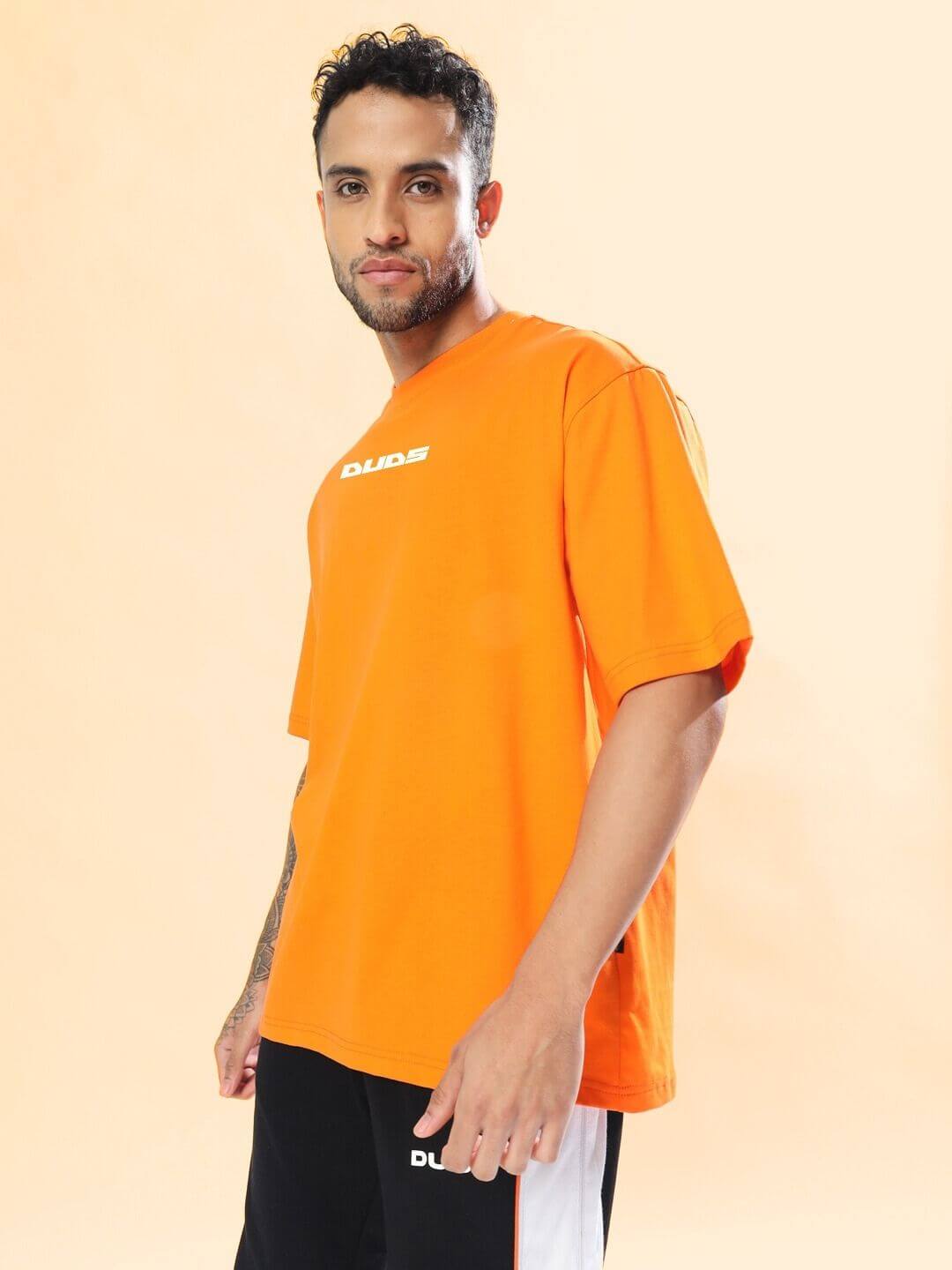 Model wearing MACLERAN PRINTED OVERSIZED T-SHIRT ORANGE, showcasing trendy streetwear style, bright orange color, and designer print.