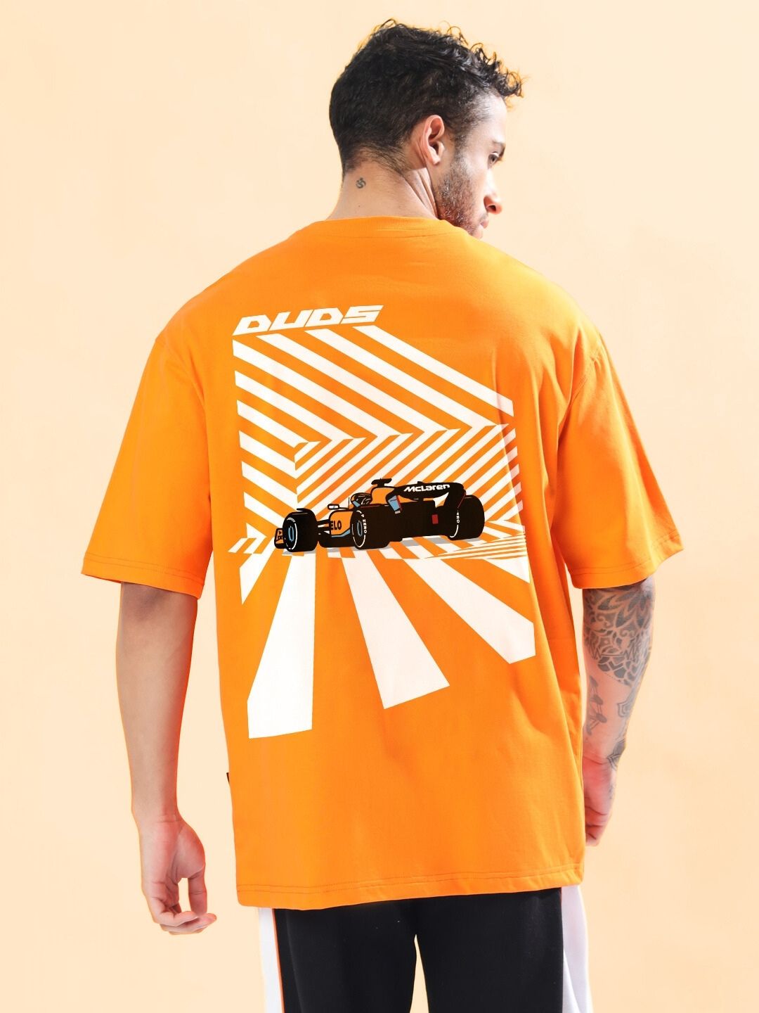 Model wearing MACLERAN PRINTED OVERSIZED T-SHIRT ORANGE with graphic design on back, showcasing bold style.