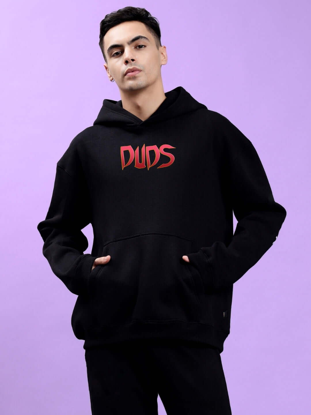 Person wearing MAFIA FLEECE OVERSIZE HOODIE BLACK, showcasing bold front graphic on a stylish purple background.