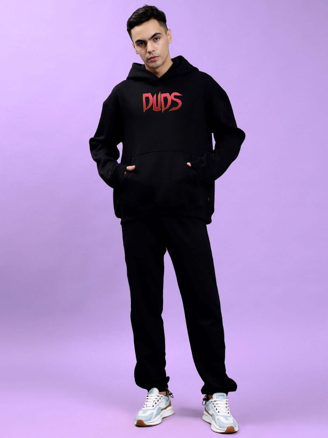 Model wearing MAFIA FLEECE OVERSIZE HOODIE BLACK with bold graphic on purple background, showcasing trendy oversized fit.