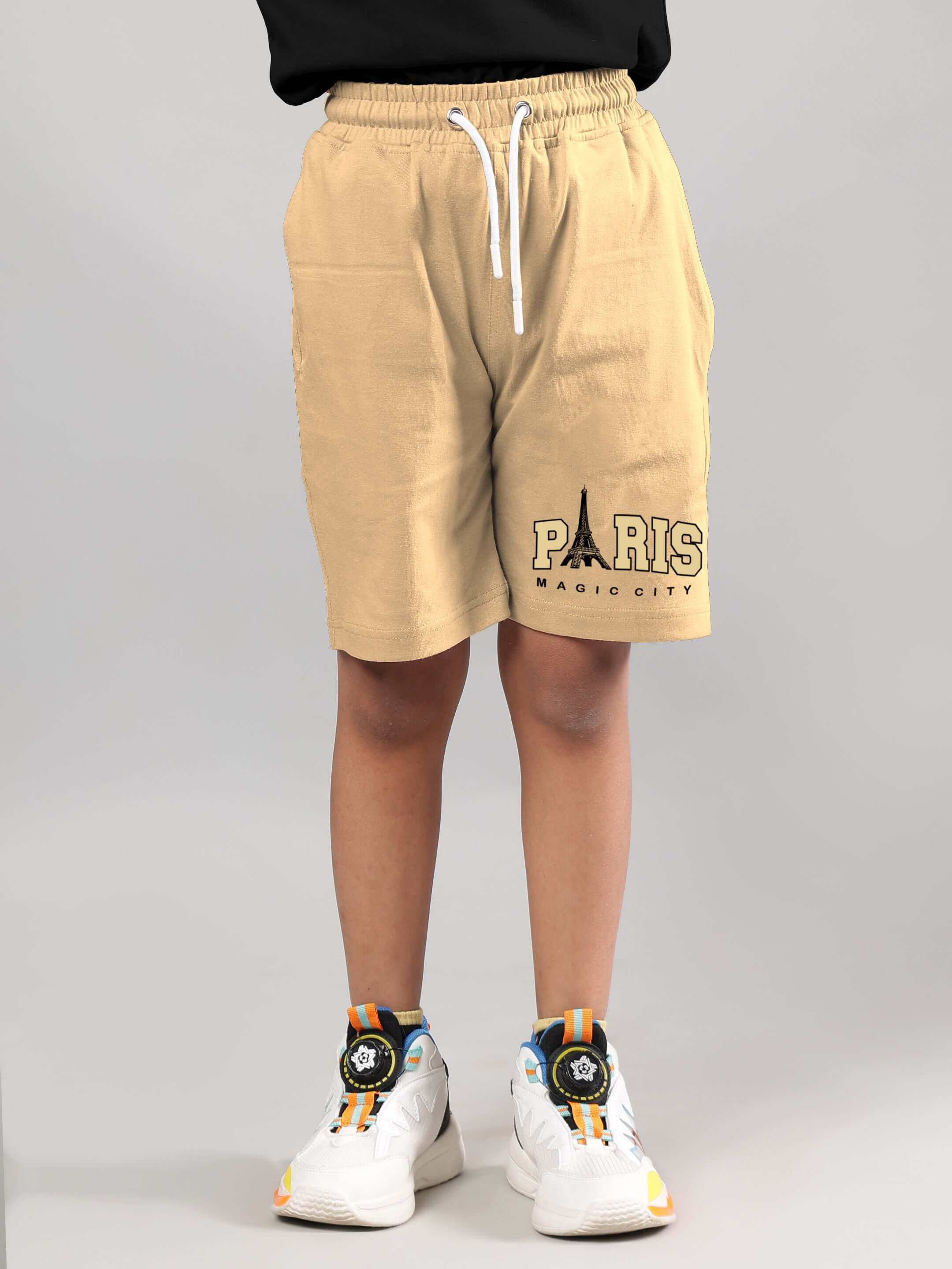 Child wearing beige shorts with "Paris Magic City" print, part of the MAGIC CITY CO-ORD for Boys & Girls.