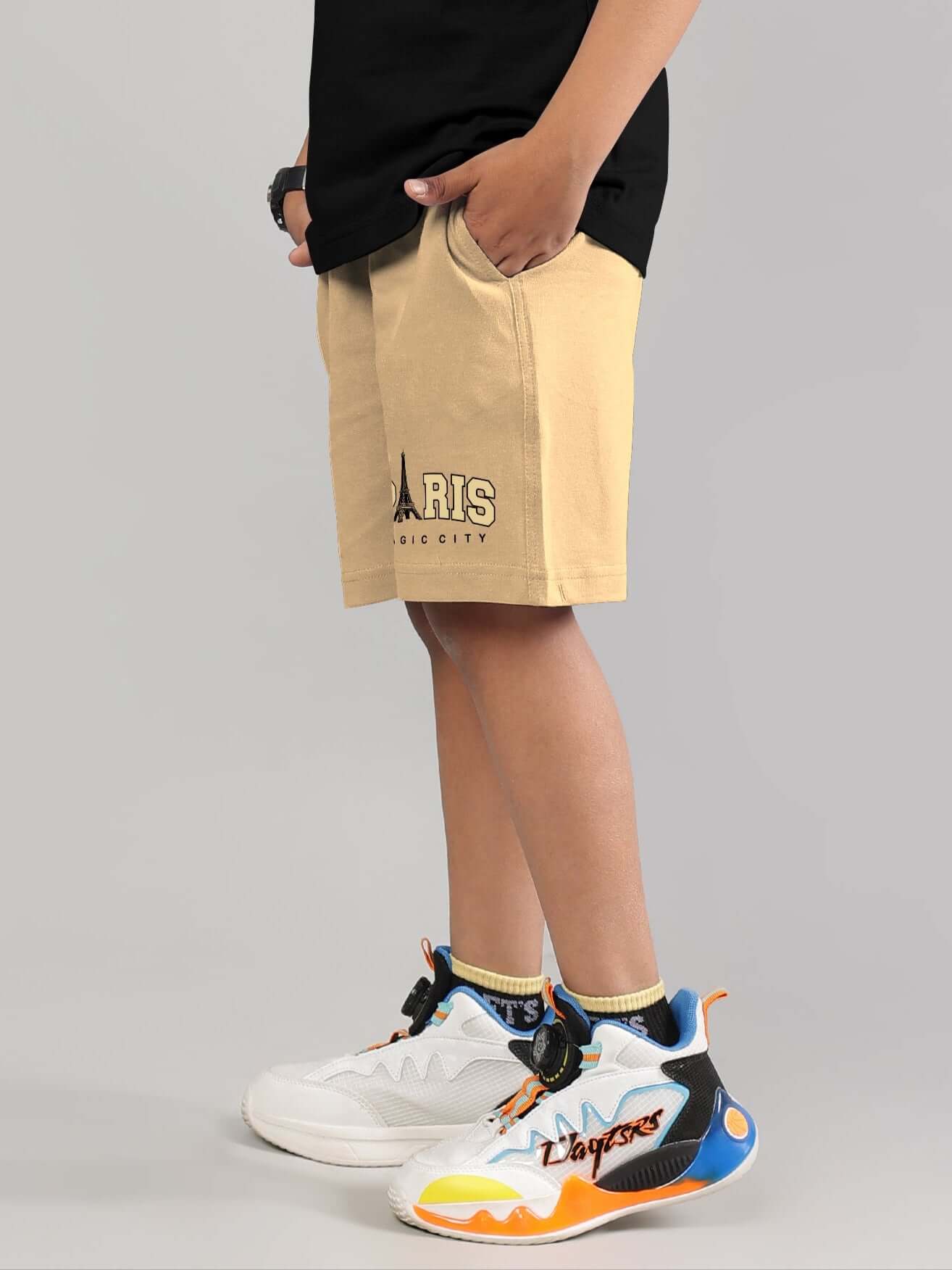 Child wearing MAGIC CITY SHORTS FOR BOYS GIRLS BEIGE, paired with colorful sneakers.