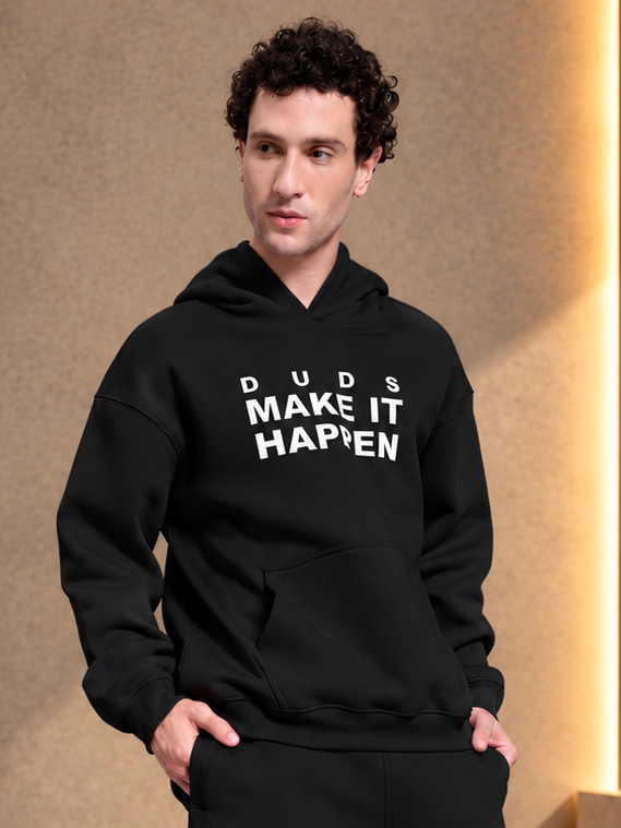 MAKE IT HAPPEN FLEECE HOODIE BLACK worn by model with curly hair, stylish casual streetwear fashion look
