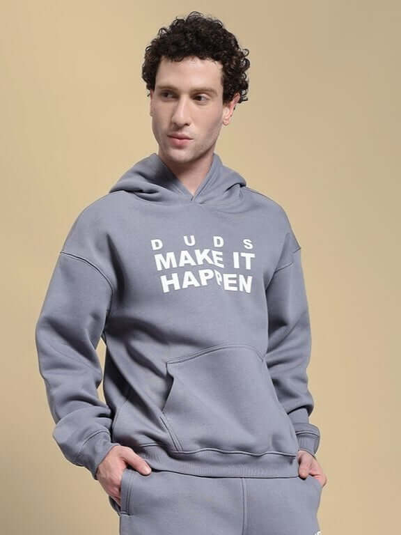 Alt Tag: Man wearing Make It Happen Fleece Hoodie Grey with hands in pockets, showcasing the hoodie’s design and comfort.