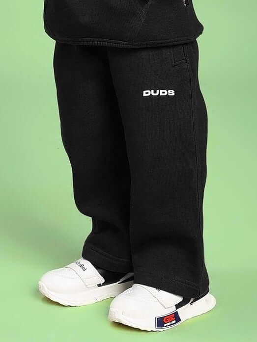 Child wearing MAKE IT HAPPEN FLEECE JOGGER FOR BOYS AND GIRLS BLACK with sneakers, showcasing street-style comfort and versatility.