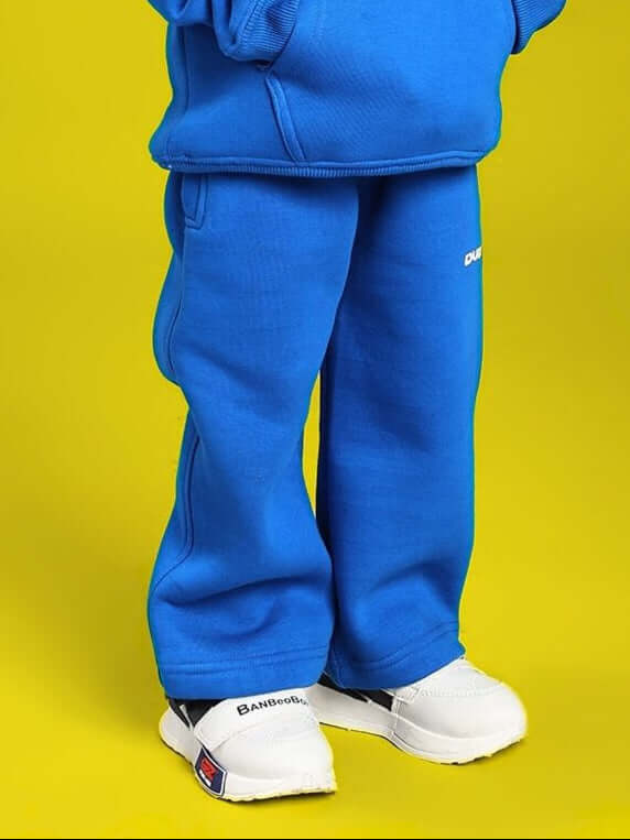 Boy wearing MAKE IT HAPPEN FLEECE JOGGER FOR BOYS AND GIRLS ROYAL BLUE, standing against a yellow background.